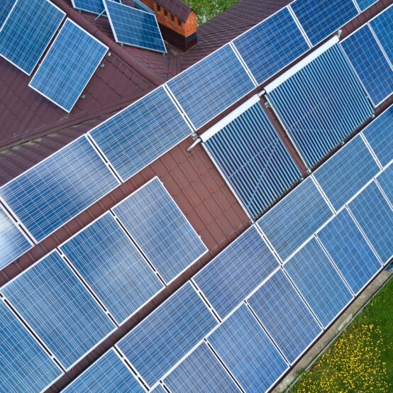 Aerial view building roof with rows of blue solar photovoltaic panels for producing clean ecological electric energy. Renewable electricity with zero emission concept.